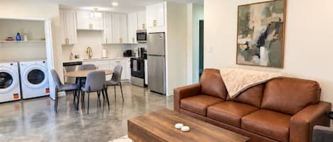 A modern living room with a brown leather sofa, a wooden coffee table, and a gray armchair.