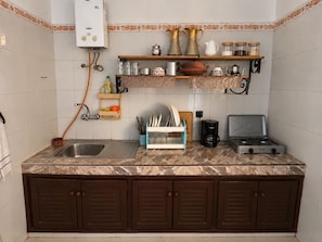 A kitchen with a built-in gas stove, a sink, and a cabinet with a towel rack.