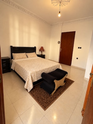 A bedroom with a bed, nightstands, a lamp, a door, and a rug.