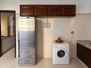 A compact kitchen with a refrigerator, washing machine, and a small oven. - Moroccan Home • Central Tangier + Free Parking (Tanger)