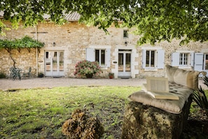 A stone building with a garden area, outdoor seating, and a book on a rock. - New Listing (Milhac-de-Nontron)