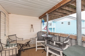 A covered outdoor seating area with chairs and a table, a fan, and a hanging decoration. - Bayside 1BR Condo with Pool (Ocean City)