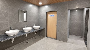 A modern bathroom with three sinks, a mirror, and a door marked 'GENTHS'.