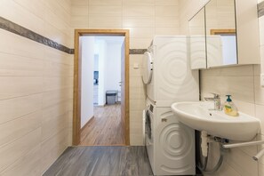 A compact bathroom with a washing machine, a sink, and a mirror. - New Listing (Mainz)