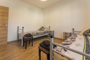 A small, single-room accommodation with a bunk bed, a wooden wardrobe, a small table, and a bench. - New Listing (Mainz)