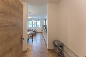 A hallway leading to a kitchen with a dining area, wooden flooring, and pendant lighting. - New Listing (Mainz)