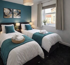Een hotelkamer met twee bedden, een raam met gordijnen en kunst aan de muur.