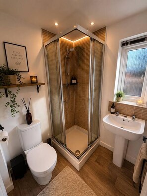 A modern bathroom with a glass-enclosed shower, a white toilet, a sink, and a window. - Prime Location Modern Home, Sleeps 5, Free Parking (Coventry)