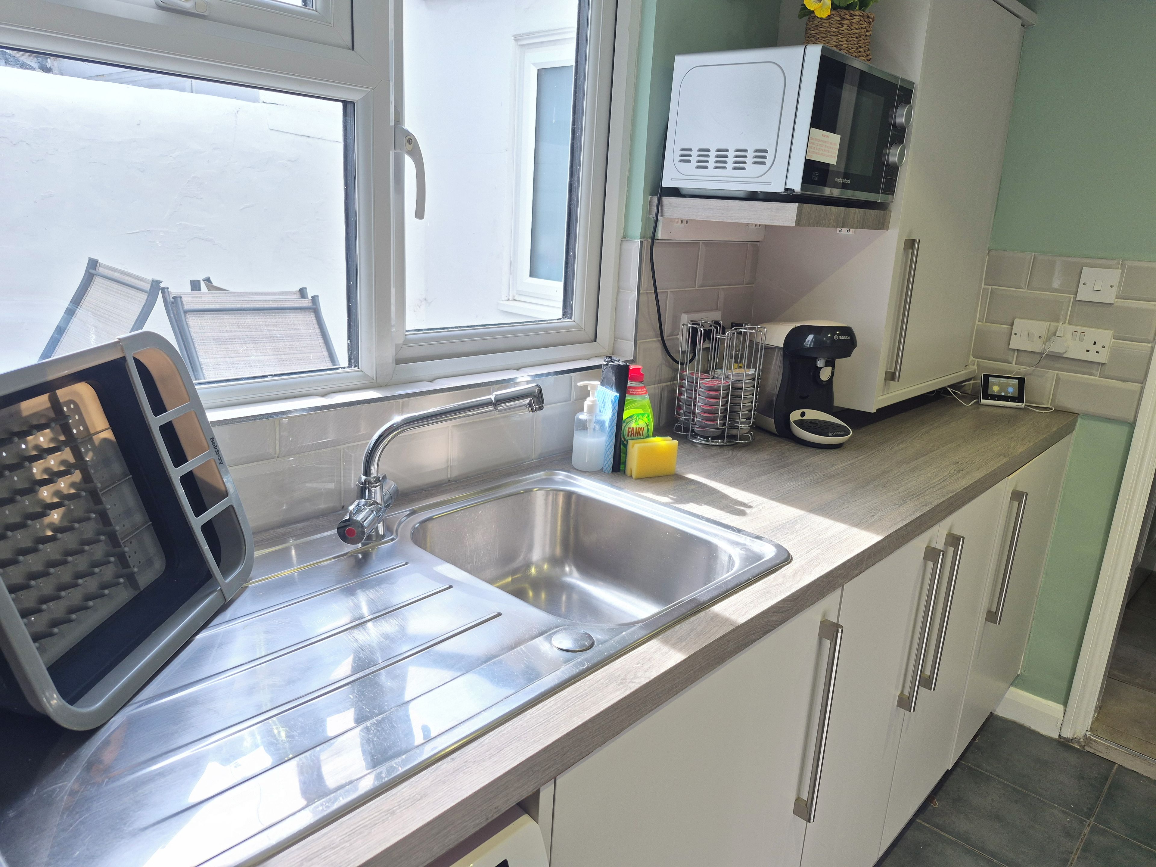 A kitchen with a stainless steel sink, a toaster, a microwave, and a coffee maker.