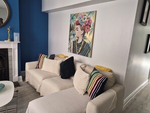 A living room with a blue accent wall, a fireplace, a sofa set, and a painting. - COSY STATION ESCAPE (Brighton and Hove)