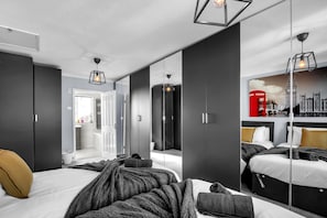 Ein modernes Schlafzimmer mit einem großen Bett, einem Kleiderschrank und einem Spiegel.