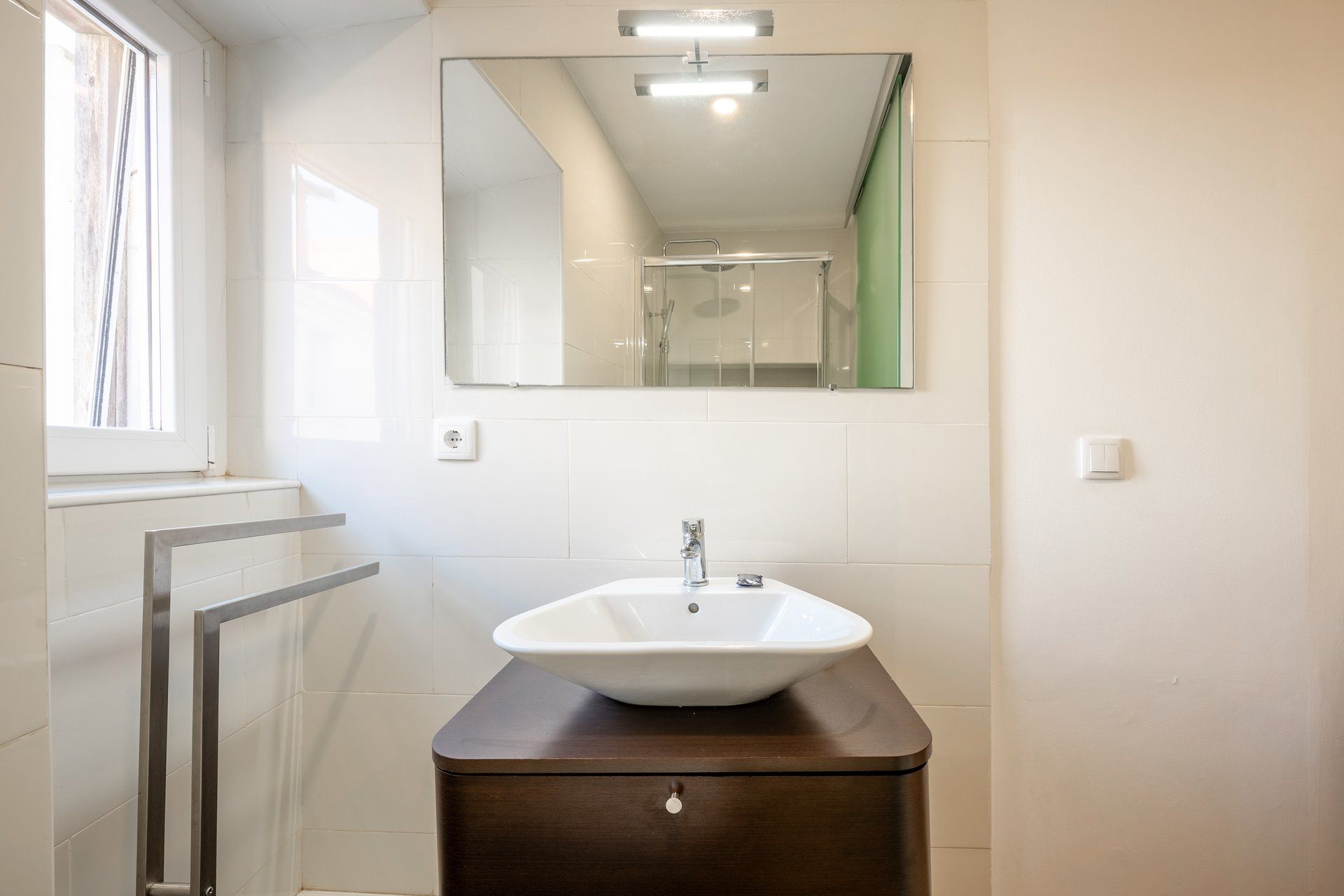 Un baño con lavamanos blanco, un espejo y ducha.