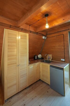 A compact kitchen with wooden cabinets, a sink, and a dishwasher.