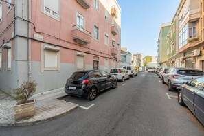 A narrow urban street lined with parked cars and multi-story buildings. - GuestReady - Cozy 3-Bedroom Apartment with Terrace (Lisbon)