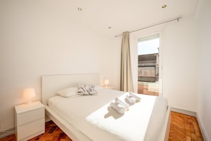 A bedroom with a bed, bedside tables, a window with curtains, and a view of the outside. - GuestReady - Cozy 3-Bedroom Apartment with Terrace (Lisbon)
