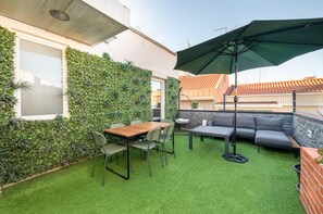 Une terrasse avec une table et des chaises, un fauteuil suspendu et un canapé.