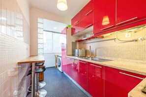 Une cuisine moderne avec des meubles de rangement rouges, un évier en acier inoxydable et un four à micro-ondes.