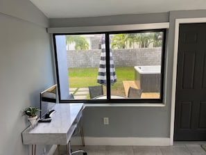 A room with a large window, a desk with a computer, a chair, and a potted plant. - Modern 4-bedroom Oasis in North Miami w/ HOT TUB (Miami)