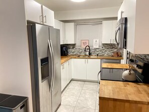 A modern kitchen with stainless steel appliances, white cabinetry, and a tiled backsplash. - Modern 4-bedroom Oasis in North Miami w/ HOT TUB (Miami)