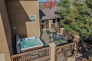 A hot tub on a patio with a table and chairs, surrounded by a wooden fence. - Mountain Views - Hot Tub Two Game Rooms (Monument)