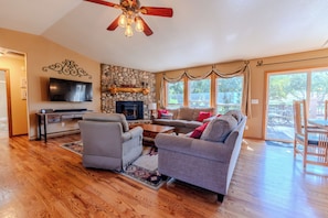 A spacious living room with a stone fireplace, a flat-screen TV, and a ceiling fan. - Mountain Views - Hot Tub Two Game Rooms (Monument)
