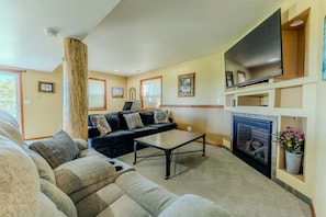 A living room with a sofa, a coffee table, a fireplace, and a television. - Mountain Views - Hot Tub Two Game Rooms (Monument)