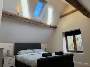 A bedroom with a sloped ceiling, a bed, a nightstand, and a window. - Woodland Forge - The Stables (Over Whitacre)