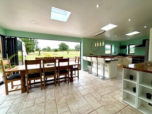 A spacious kitchen with a dining area, large windows, and a view of the outdoors. - Woodland Forge - The Stables (Over Whitacre)