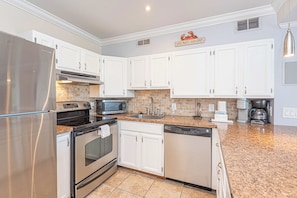 A modern kitchen with white cabinets, stainless steel appliances, and a granite countertop. - Bayview 2BR Condo Close to Beach (Ocean City)