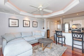 A modern living room with a sectional sofa, a coffee table, and a ceiling fan. - Bayview 2BR Condo Close to Beach (Ocean City)