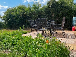 An outdoor patio with metal furniture and a garden area.