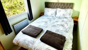 A bedroom with a bed, a window with curtains, a radiator, and a headboard.