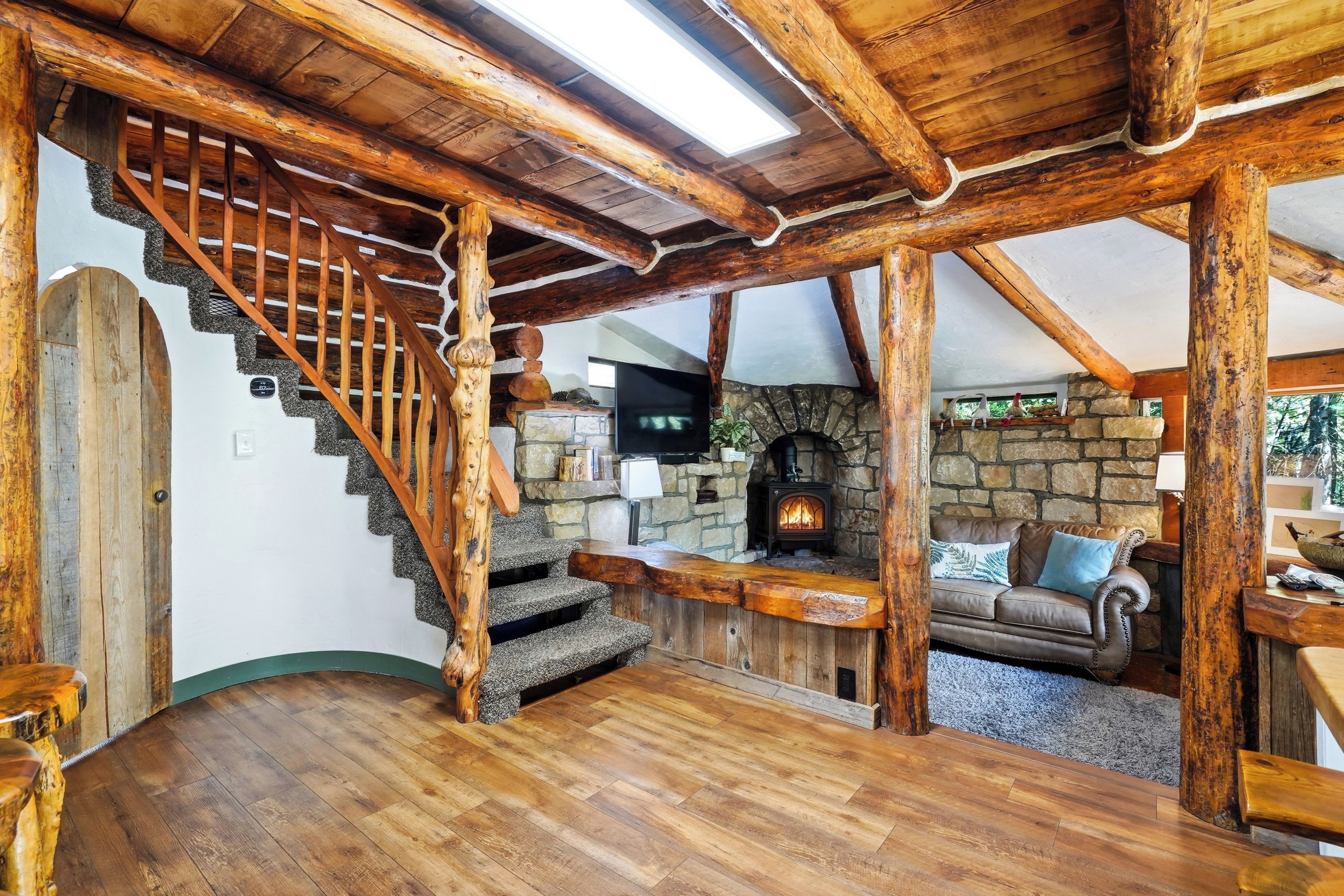 Un interior rústico con una escalera de madera, una chimenea de piedra y un sofá de cuero.