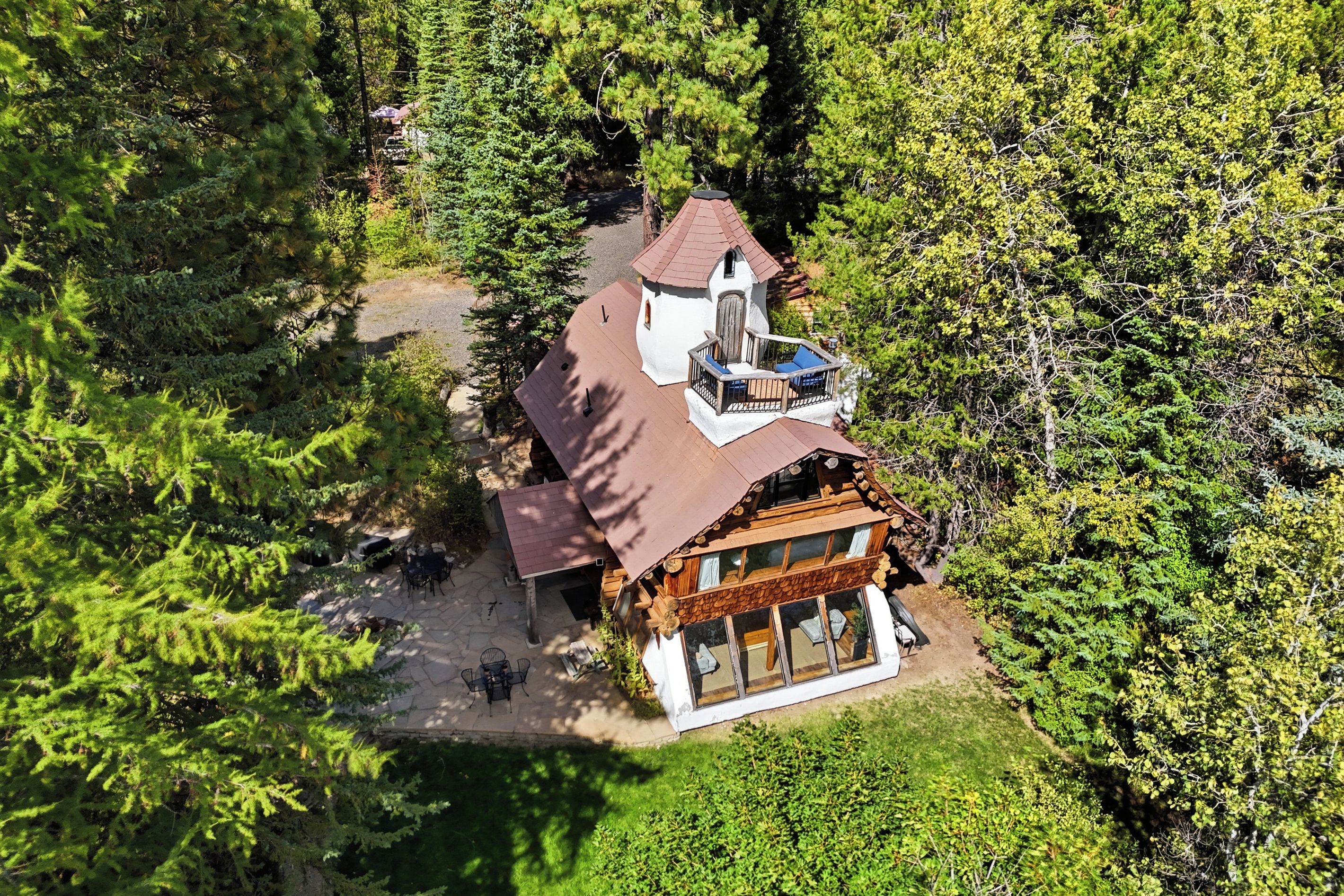 Eine zweistöckige Holzhütte mit Balkon, umgeben von dichtem Wald.