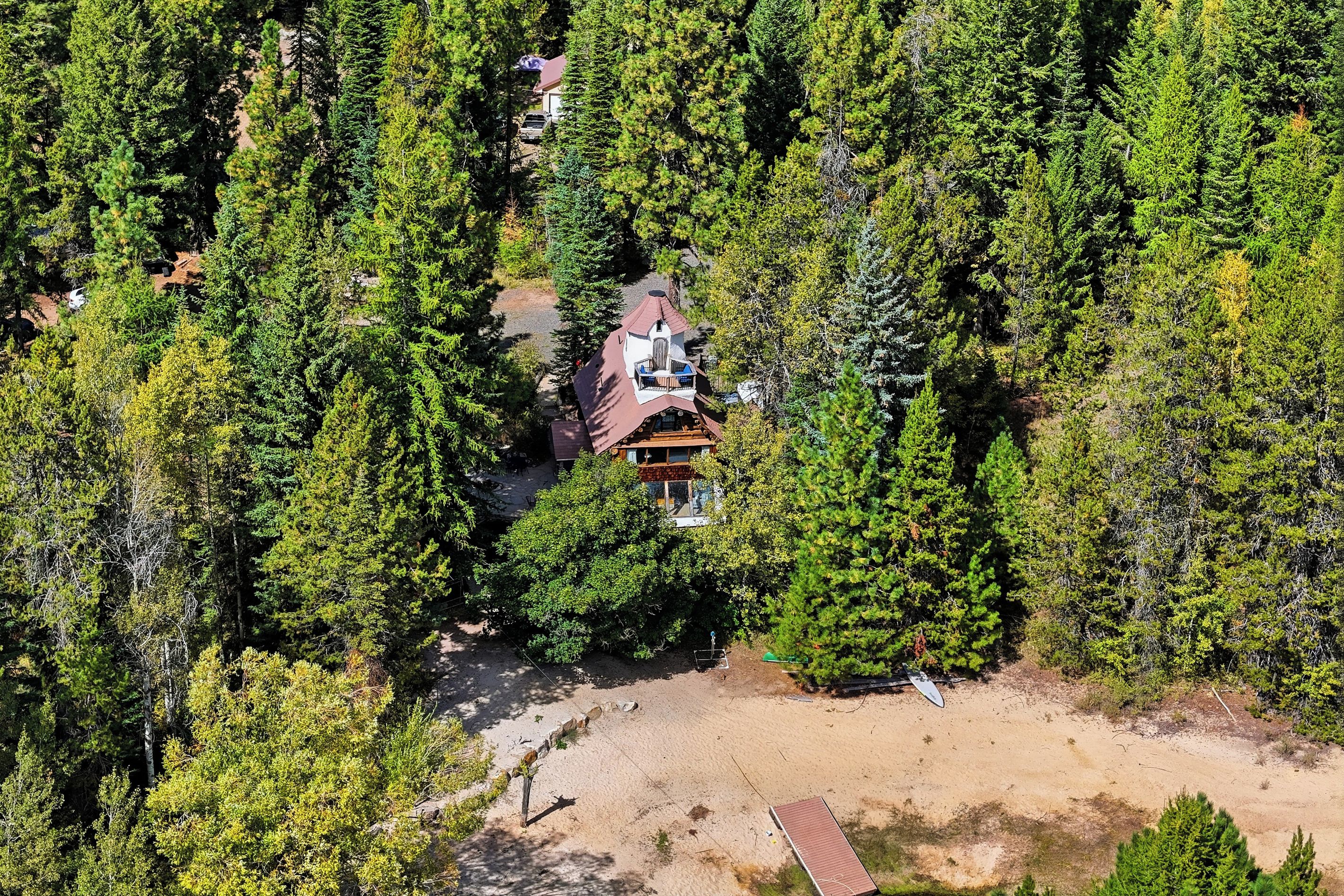 Una cabaña apartada rodeada de un bosque denso, con un sendero de tierra que lleva a la entrada.