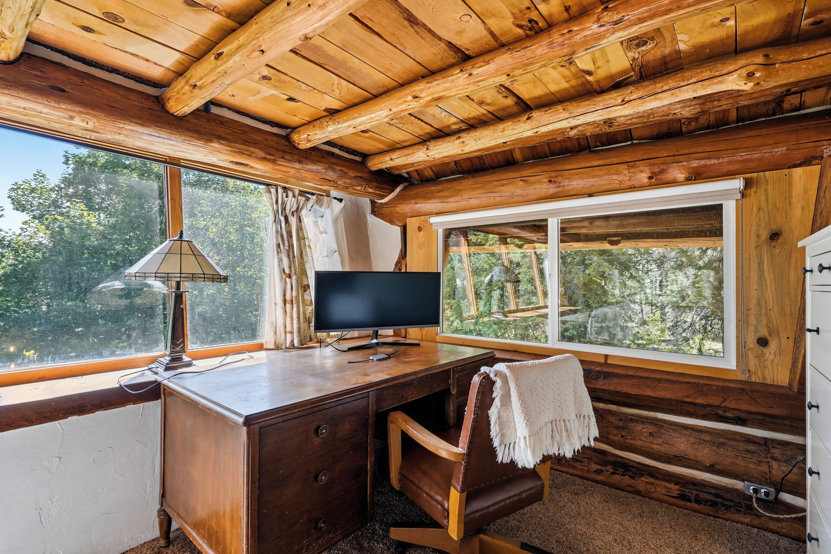 Ein Holzhütten-Innenraum mit Schreibtisch, Stuhl und Fernseher.