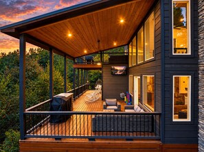 A modern house with a wooden deck, outdoor seating, and large windows. - Amazing Views from 3 Decks | Sauna | Hot Tub (Broken Bow)