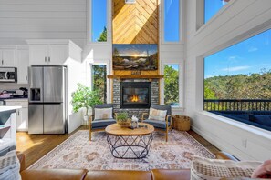 A modern kitchen with stainless steel appliances, a stone fireplace, and a view of the outdoors. - Amazing Views from 3 Decks | Sauna | Hot Tub (Broken Bow)