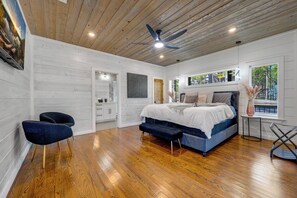 A bedroom with a wooden ceiling, a bed, a bench, a chair, and a window with a view. - Amazing Views from 3 Decks | Sauna | Hot Tub (Broken Bow)