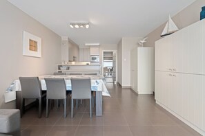 A modern kitchen with a central island, a dining area with a table and chairs, and a large white wardrobe. - 2 bedroom accommodation in Nieuwpoort (Nieuwpoort)
