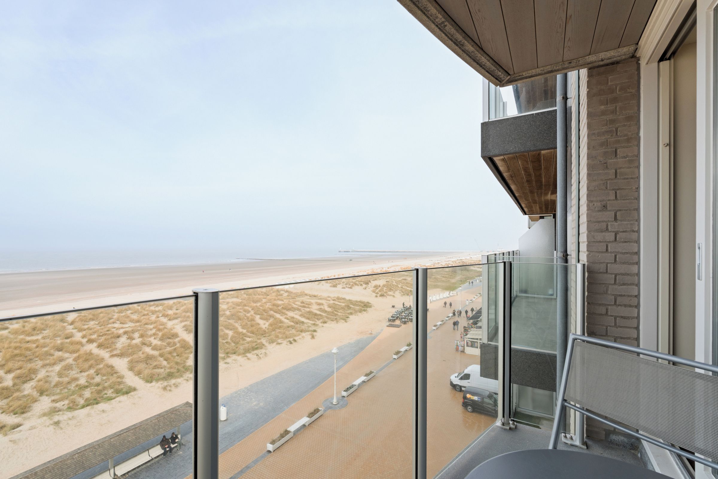 A balcony with a view of a beach and dunes.