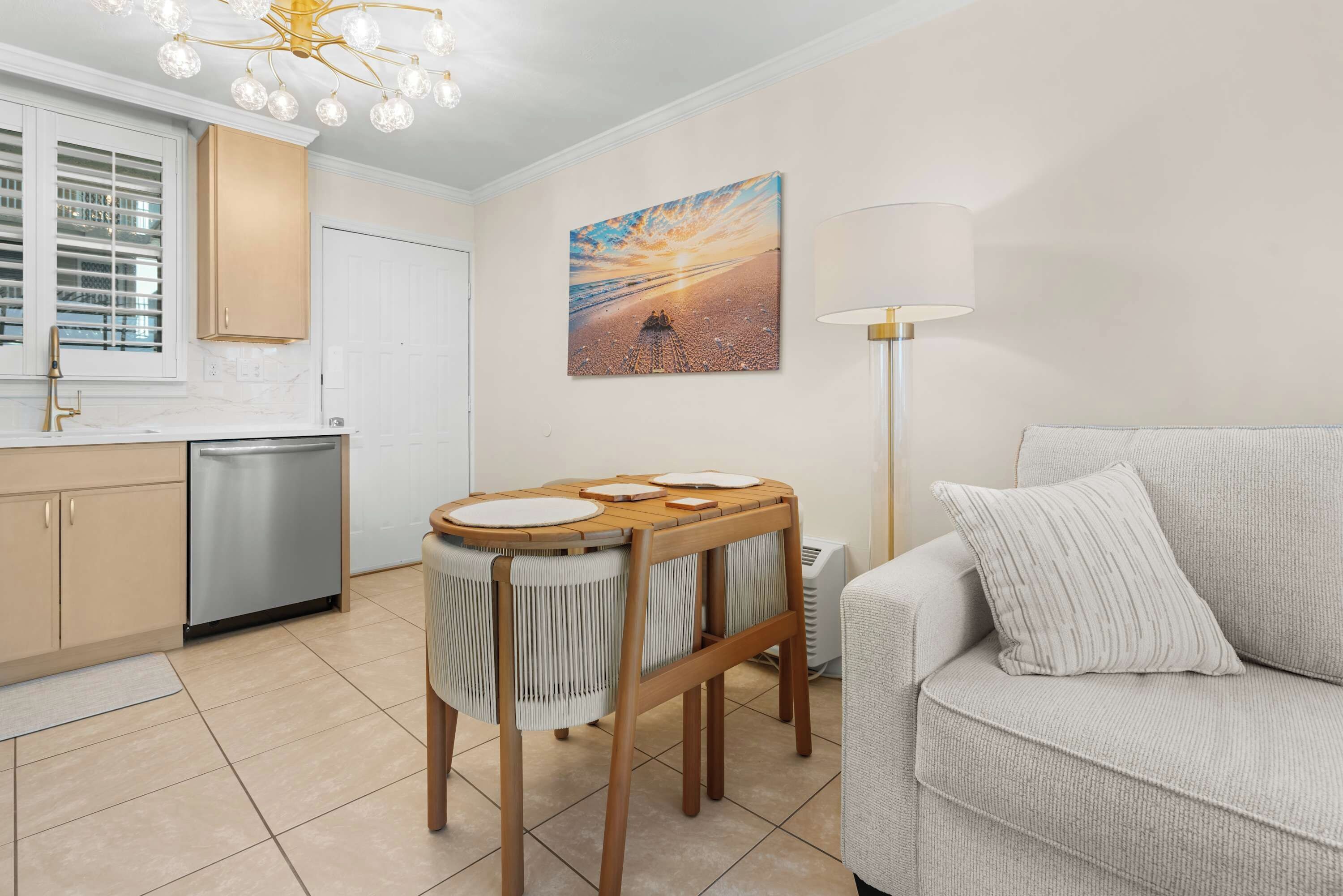 A modern kitchen with a dining area, a sofa, and a painting on the wall.