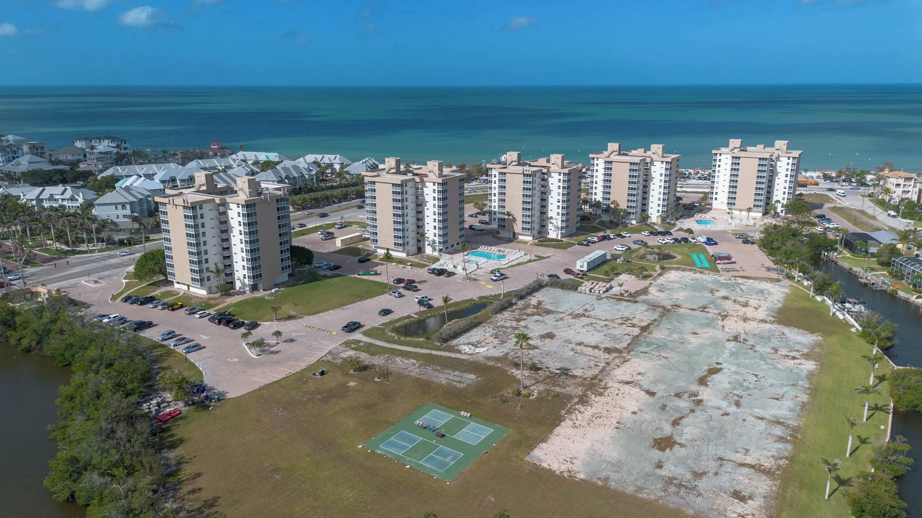 Un quartier résidentiel situé sur la côte, avec de grands immeubles, un parking et une plage.