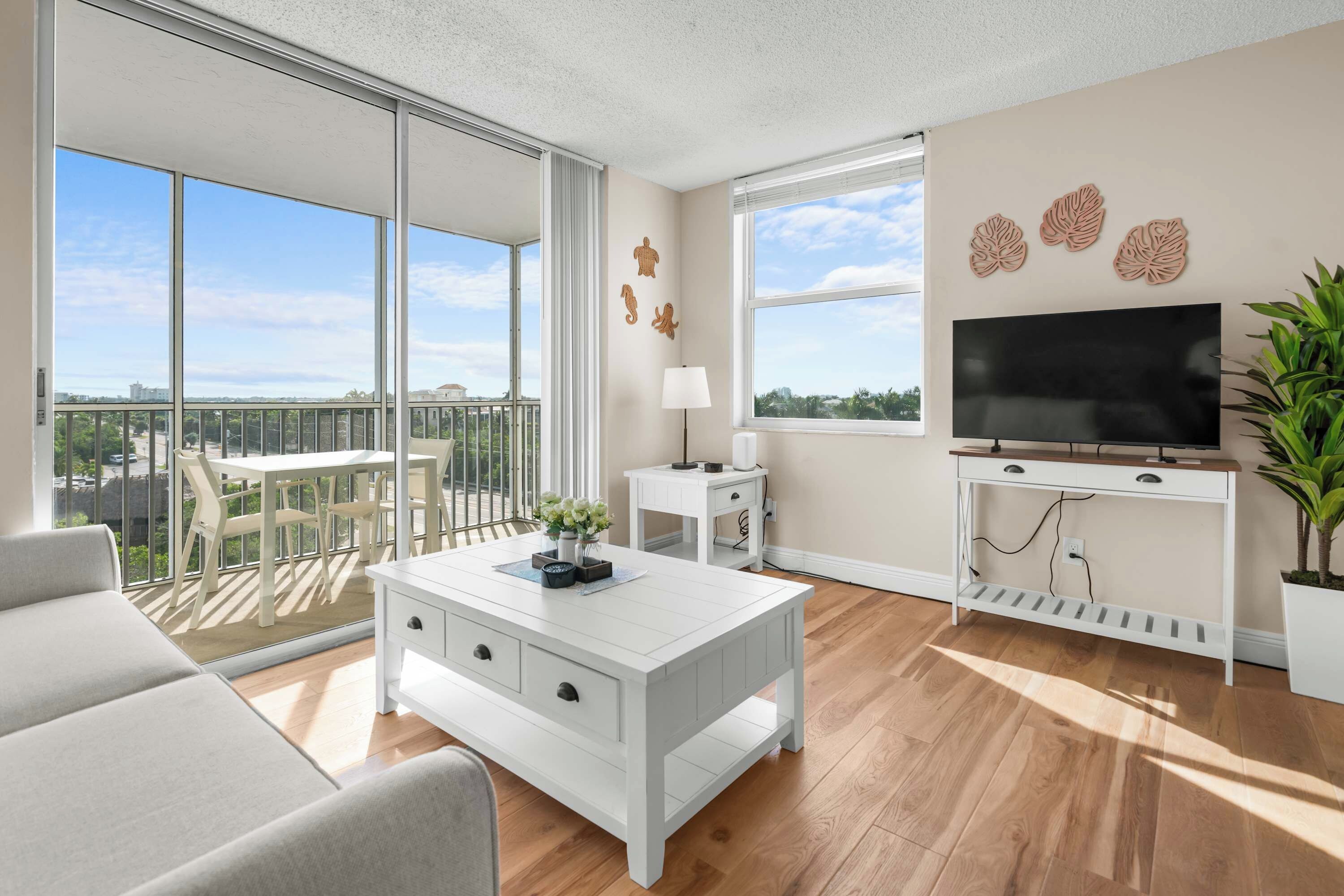 A modern living room with a balcony, a flat-screen TV, and a dining area.