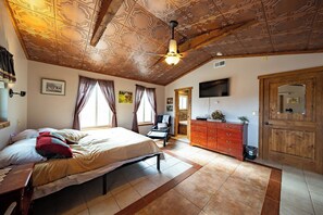 Ein Schlafzimmer mit einem Bett, einem Schminktisch, einem Fernseher und einer Decke mit aufwendigen Mustern.