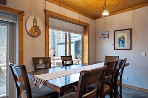 A dining room with a wooden table and chairs, a hanging light fixture, and framed pictures on the walls. - Mountain Retreat 5BR • Hot Tub • 25 Min to PC (Coalville)