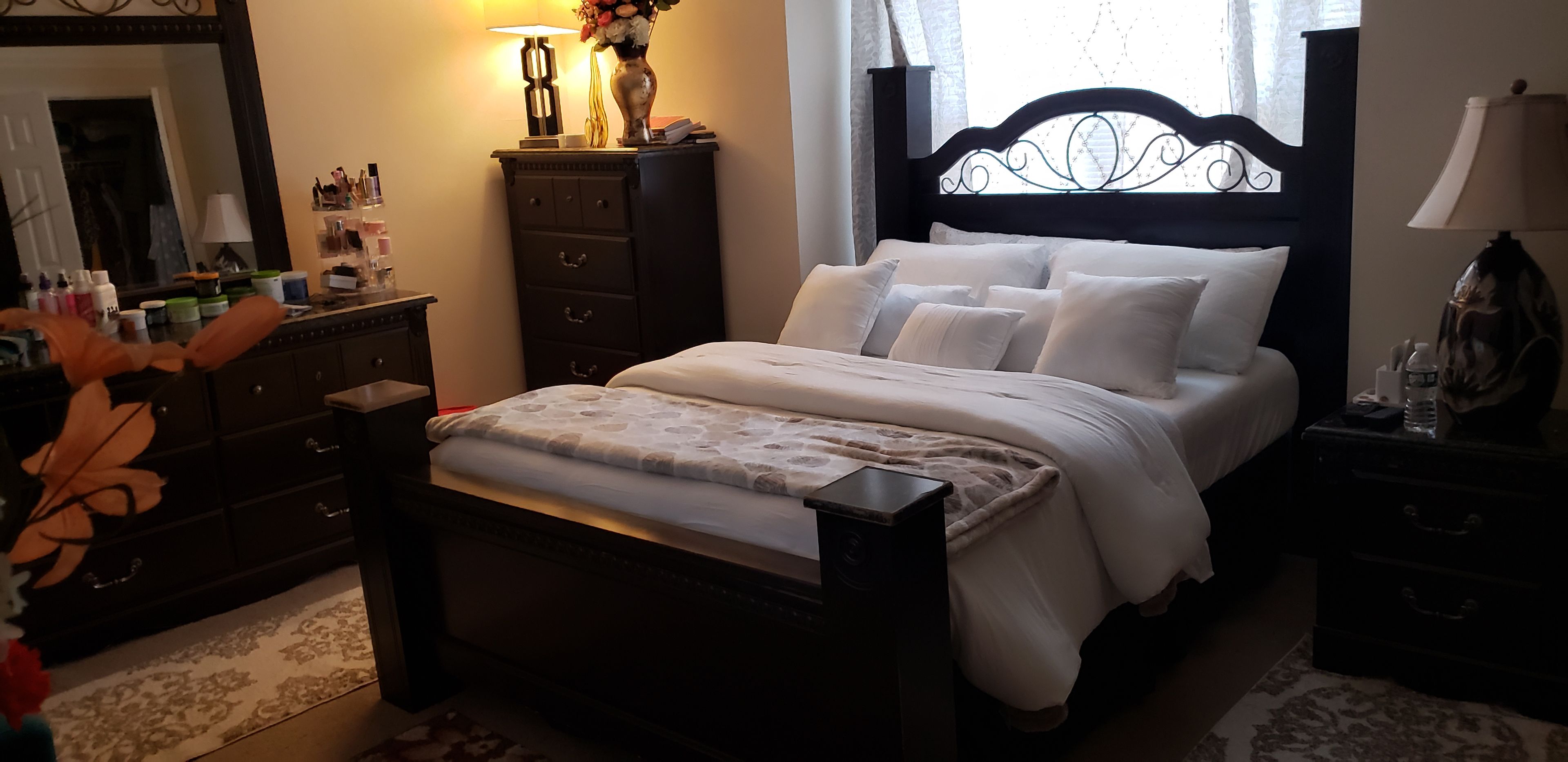 A bedroom with a bed, dresser, nightstand, and a mirror.