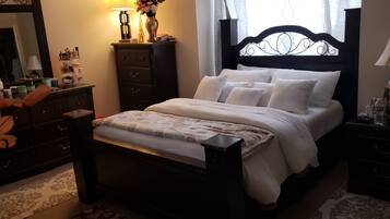 A bedroom with a bed, dresser, nightstand, and a mirror.