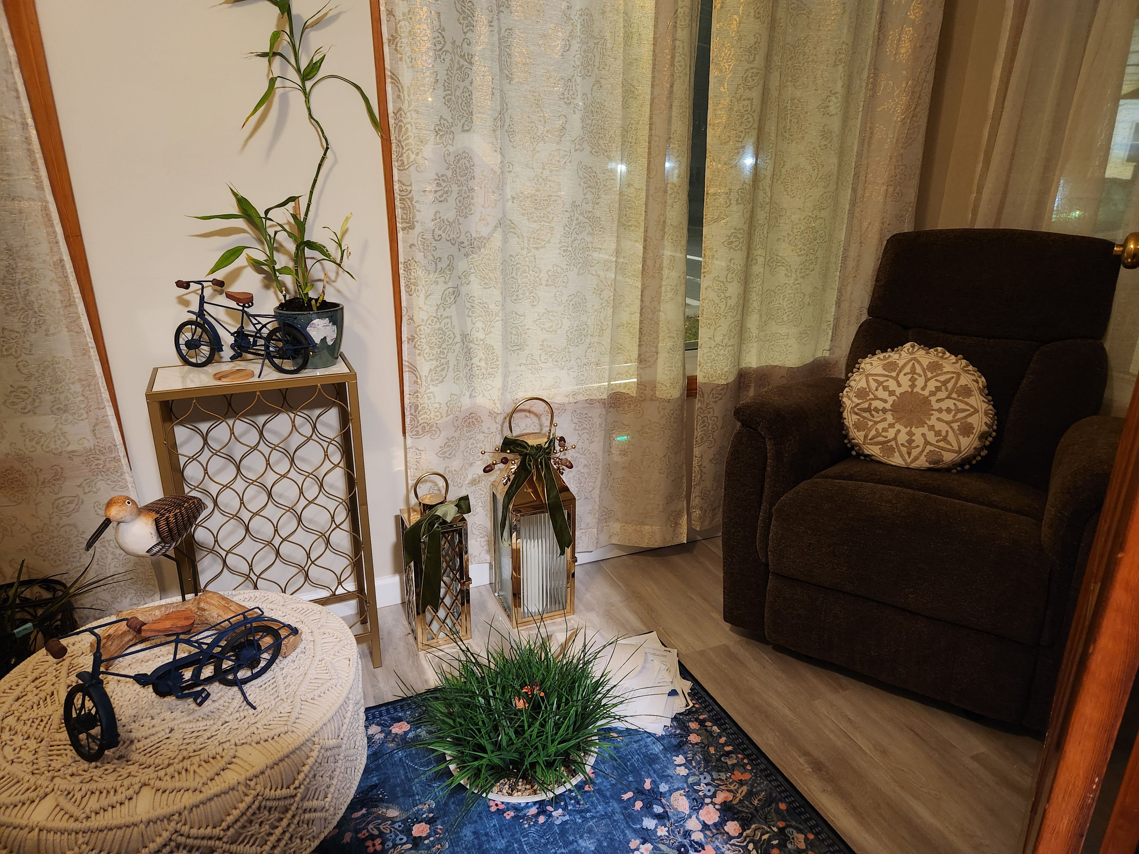 Una sala de estar acogedora con un sillón marrón, una mesita con objetos decorativos, una bicicleta y una planta en maceta.