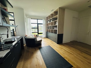 A modern kitchen with a built-in oven, a dining area with a black chair, and a large window. -  Room with ultra-modern amenities . Newly built house -facing Tampa river. (Tampa)